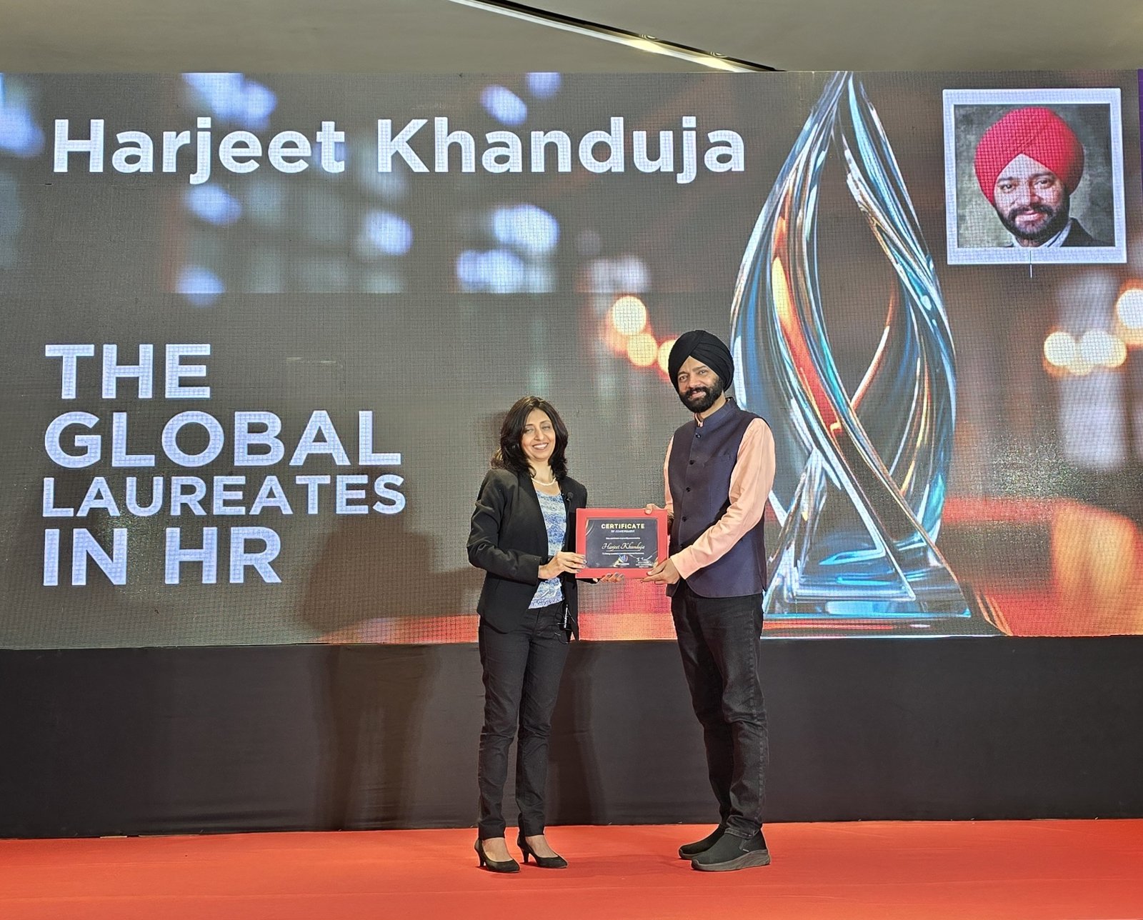 Harjeet receiving the Global Laureate in HR certificate on stage