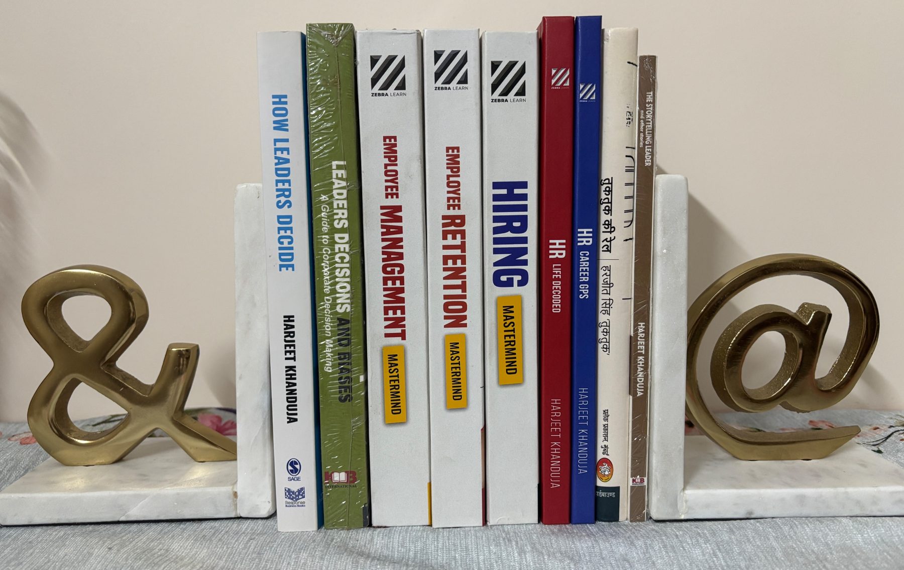 Harjeet Khanduja's books on a shelf, from How Leaders Decide to the HR Mastermind series, HR Career GPS and Tuktuk Ki Rail