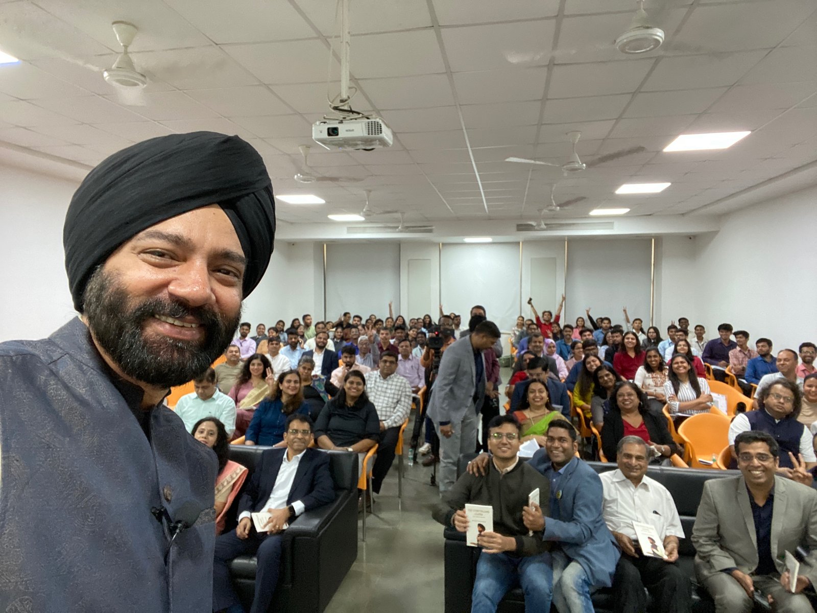 Harjeet taking a selfie with a smiling audience holding his book