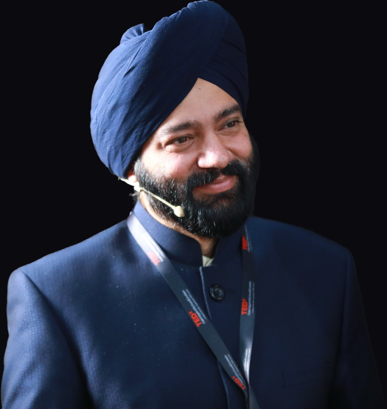 Harjeet smiling with a headset microphone and TEDx lanyard