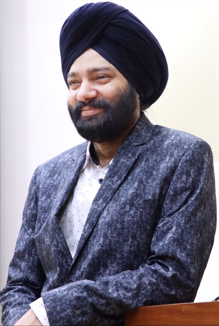 Harjeet at the lectern in a grey blazer